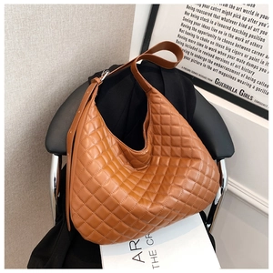 Detail of caramel quilted hobo shoulder bag with glossy faux leather and wide strap