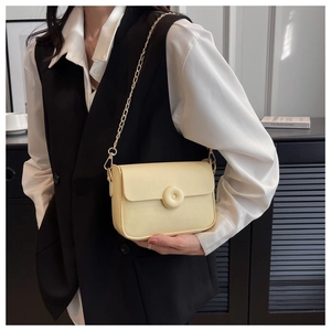 Macro view of creamy yellow leather crossbody bag featuring a unique round ring buckle closure
