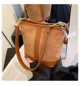 Detailed close-up of brown suede patchwork bucket bag with gold hardware and strap