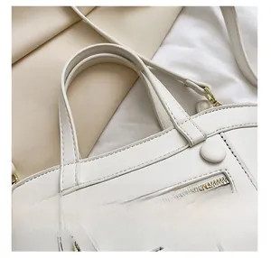 Détail d'un sac à main blanc en simili cuir avec poignées renforcées et fermeture éclair