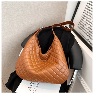 Brown quilted tote bag styled on a blazer with art books for a modern office aesthetic