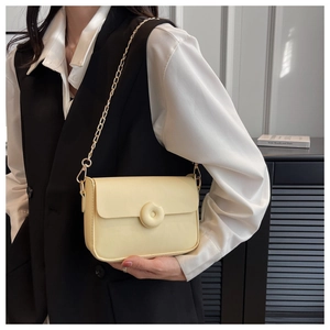 Detail view of cream leather crossbody bag with chain strap and circular ring ornament