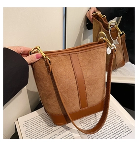 Detail of brown patchwork bucket bag with smooth leather and suede on an open book
