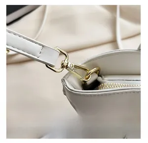 Détail du crochet en métal doré et des coutures précises sur un sac à main blanc