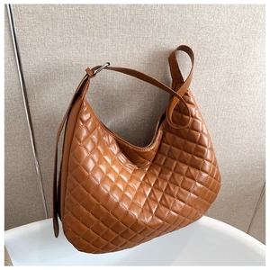 Detail of a brown quilted hobo bag featuring large diamond stitching and a silver buckle