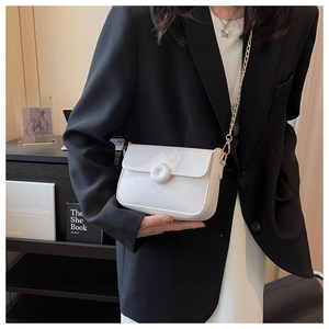 Detail of cream white crossbody square bag with gold chain strap on a black blazer