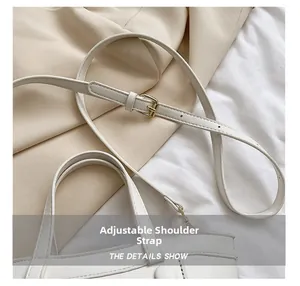 Détail de la bandoulière réglable avec boucle en métal et double poignée sur le sac blanc