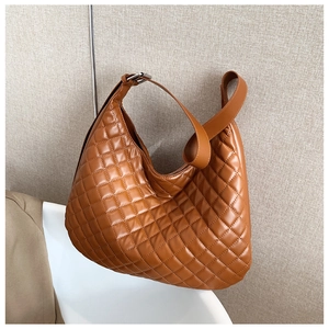 Detail of a brown quilted hobo bag featuring a soft leather texture and adjustable strap