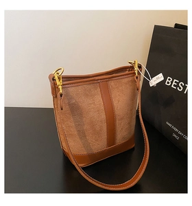 Detail of vintage brown bucket bag with mixed textures, gold hardware and leather strap
