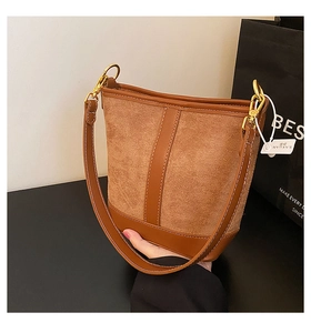 Detail of brown bucket bag showing contrast stitching and gold metal hardware hook