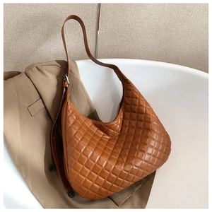 Detail of tan quilted tote bag on blazer showing soft leather texture and large capacity