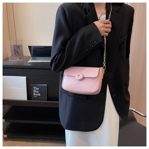 Detail of pink leather crossbody bag with round buckle and elegant gold chain strap