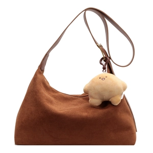 Brown matte suede tote bag with adjustable strap and cute plush charm on white background