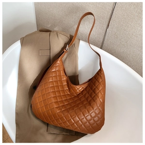 Detail of caramel brown quilted hobo bag with diamond pattern and silver metal buckle