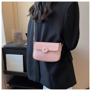 Detail of light pink small square crossbody bag with gold chain and round padded button