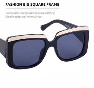 Détail de lunettes de soleil carrées avec monture noire épaisse et barre dorée en métal