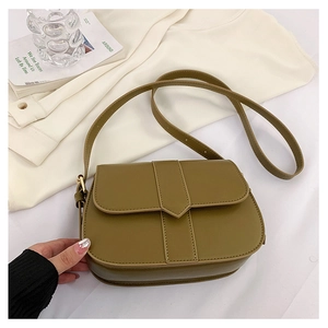 Detailansicht einer braunen Vintage-Satteltasche auf weißem Stoff mit dekorativem Pfeilriemen