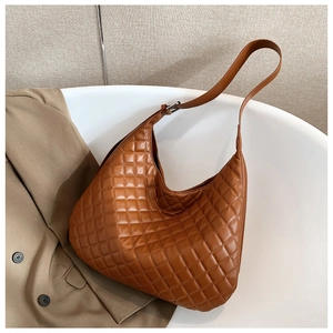 Detail of a brown quilted hobo shoulder bag with adjustable strap and metal buckle