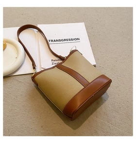Detail of color-block bucket bag with khaki lychee grain leather and caramel straps