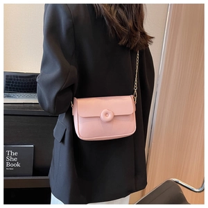 Pink crossbody square bag with chain strap shown on model over a black blazer