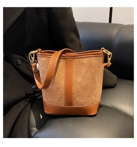 Close-up of brown bucket bag showing suede stitching and gold-tone metal hardware