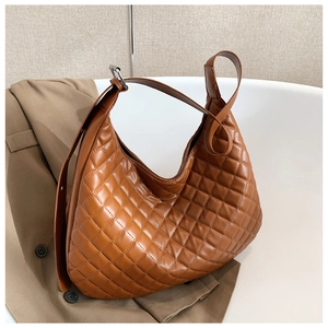 Detailed side view of a brown quilted leather shoulder bag with adjustable silver buckle strap
