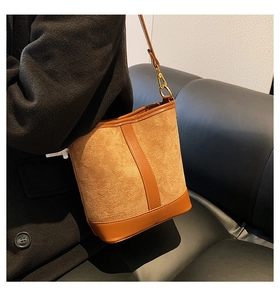 Detail of vintage brown bucket bag in suede and leather worn by a model in a dark setting