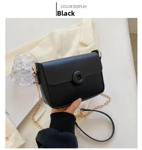 Detail of a chic black leather crossbody bag featuring a golden chain strap and round buckle
