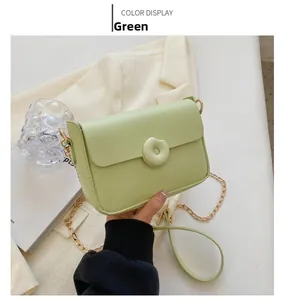Detail of light green PU leather bag featuring a round buckle and gold chain strap