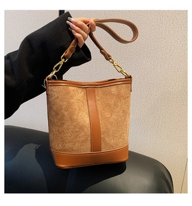 Detailed close-up of brown suede and leather bucket bag with gold metal hardware