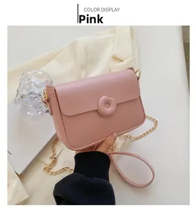 Detail of pink faux leather crossbody bag with round magnetic clasp and gold chain strap