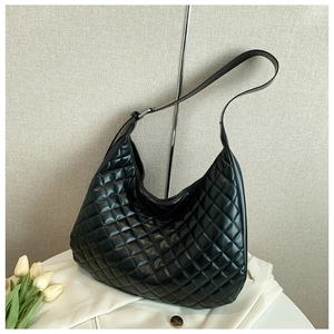 Macro detail of black quilted leather texture and adjustable silver buckle on Hobo bag