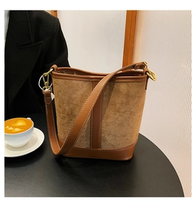 Detailed shot of brown leather bucket bag with suede patchwork and gold metal hardware
