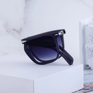 Foldable square polarized sunglasses with navy frame and gradient lenses on white stand