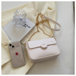 Top view of a minimalist cream-colored leather crossbody bag with chain strap and gold buckle