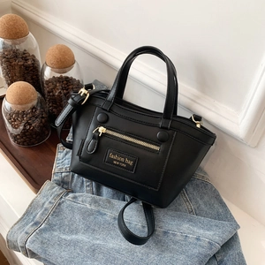 Sac à main chic en cuir noir sur denim, avec texte doré et bandoulière réglable