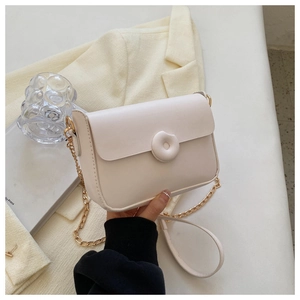 Detail of a creamy white flap bag with unique round padded button and gold chain strap