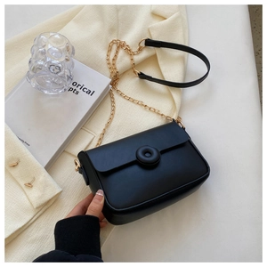 Detail of a chic black crossbody bag with a round buckle and gold chain strap