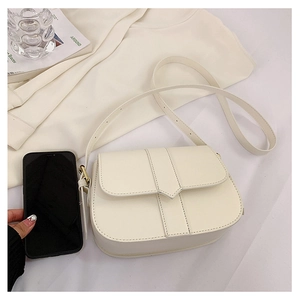 Minimalistische beige Satteltasche aus Leder mit verstellbarem Riemen auf weißem Stoffhintergrund