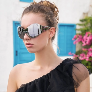 Outdoor portrait of Y2K wraparound silver mirror sunglasses with a stylish black dress