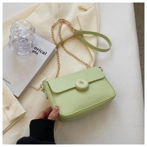 Detail of mint green crossbody bag with circular ornament and gold chain strap