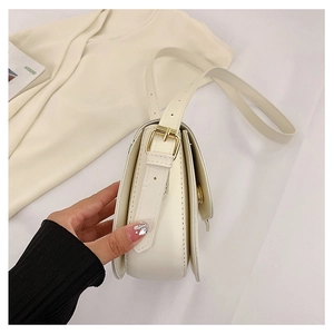 Nahaufnahme cremefarbene Schultertasche Seitenansicht mit goldener Schnalle und Design