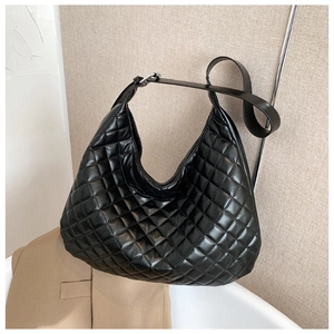 Detail of black quilted hobo shoulder bag with silver hardware and adjustable wide strap