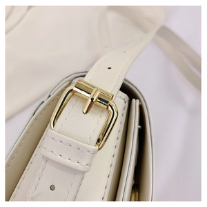 Detailansicht der beigen Ledertasche mit goldener Schnalle und präzisen Nähten