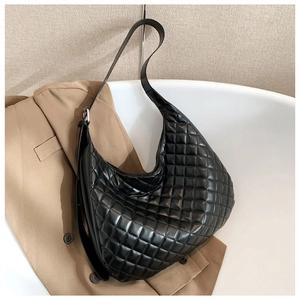 Detail of black quilted leather hobo bag with adjustable strap on suit background