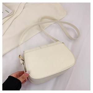 Detail einer minimalistischen cremefarbenen Satteltasche aus Leder mit goldener Metallschnalle
