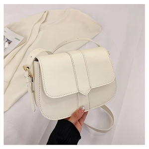 Nahaufnahme der cremeweißen Satteltasche aus Kunstleder mit goldener Schnalle und Gurt