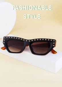Close-up of cat-eye sunglasses with black frame, gold rhinestones and gradient lenses