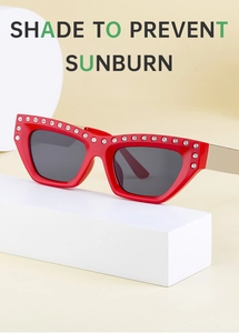 Detail of red cat-eye sunglasses with white rhinestones and gold metal temples