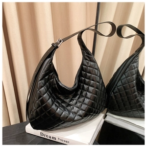 Detail of black quilted hobo bag with adjustable silver buckle strap resting on a book